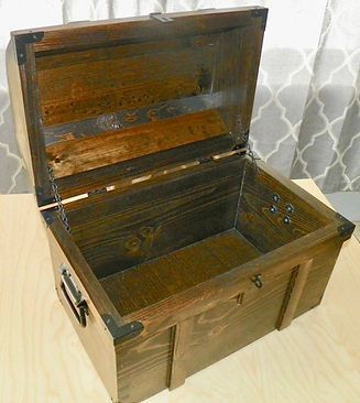 A wooden trunk with the lid open is sitting on a wooden table.