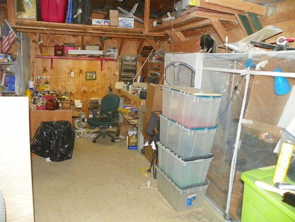 A cluttered room with a lot of plastic bins on the floor