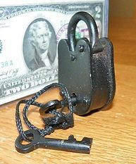 A padlock with a key attached to it is sitting next to a dollar bill.
