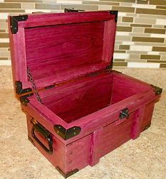 A pink wooden trunk with the lid open is sitting on a counter.