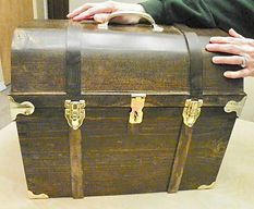 A person is holding a wooden trunk on a table.