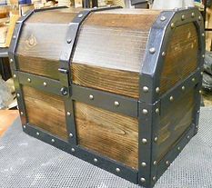 A wooden treasure chest with metal trim is sitting on a table.