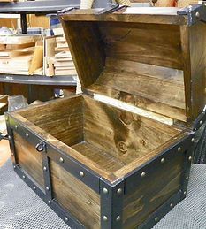 A wooden trunk with the lid open is sitting on a table.