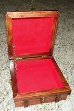 A wooden box with a red velvet lining is sitting on a carpet.