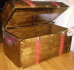 A wooden trunk with the lid open is sitting on a wooden table.