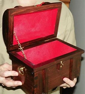 A person is holding a wooden box with a red lining
