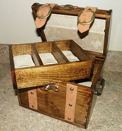 A wooden trunk filled with watches is sitting on a table.