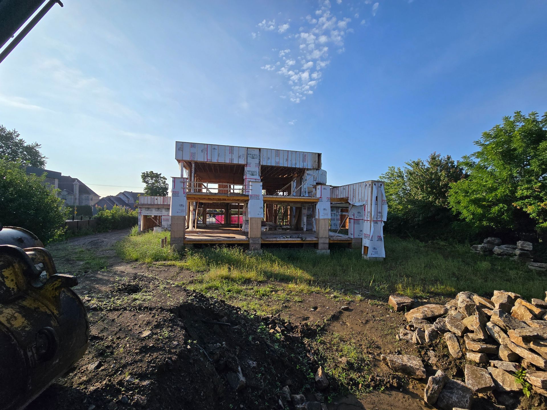 Une maison est en construction au milieu d'un champ de terre.