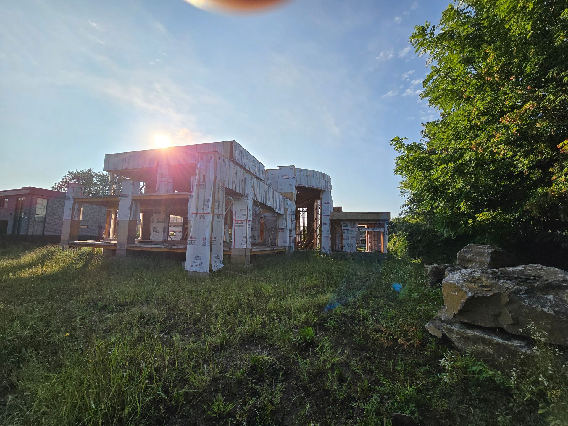 Le soleil brille à travers les arbres devant un bâtiment en construction.