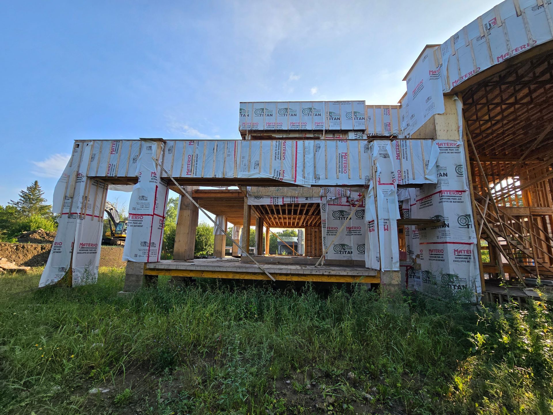 Une grande maison est en construction dans un champ herbeux.