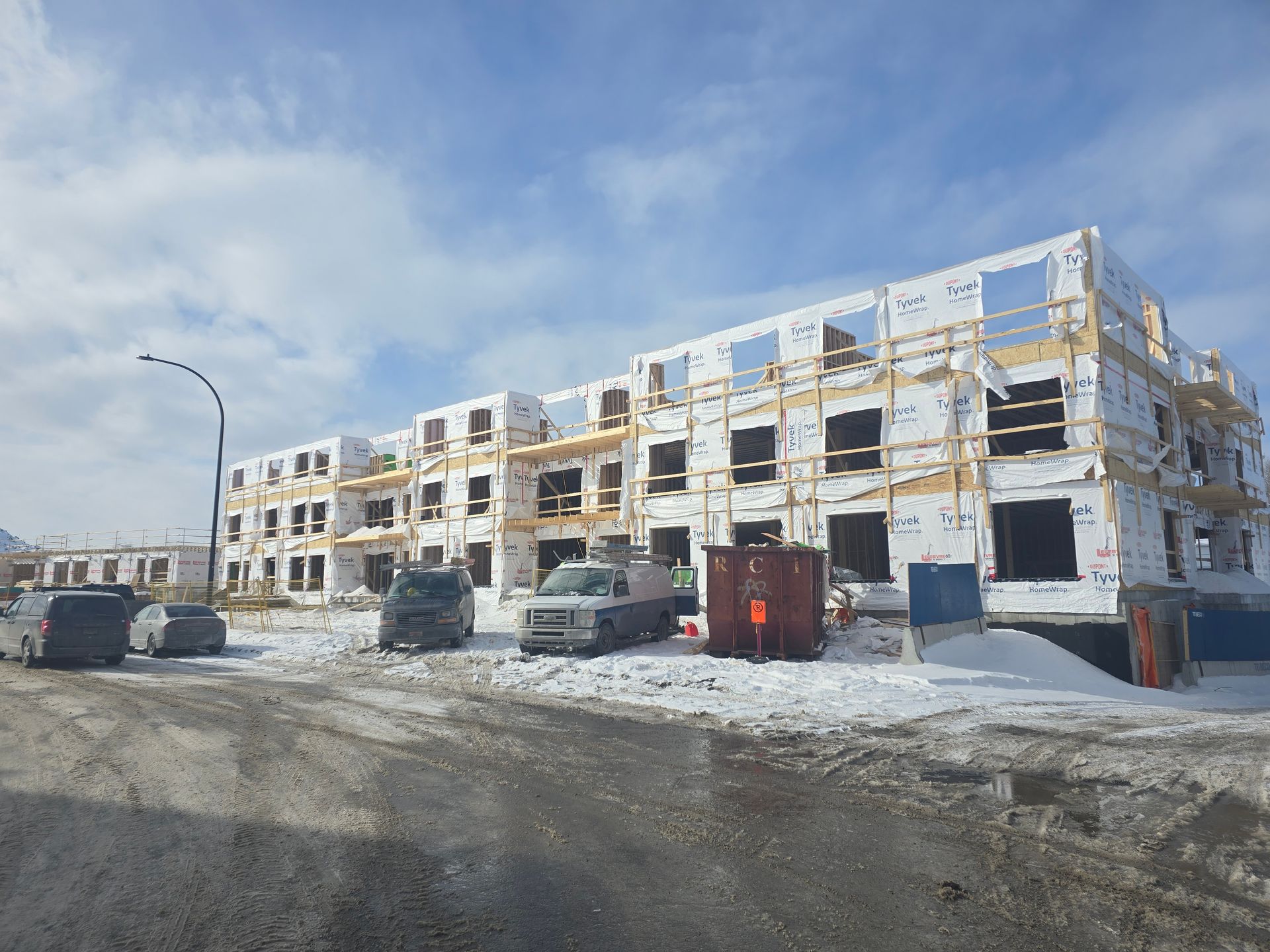 Un grand bâtiment en construction avec des voitures garées devant.