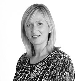 Blond woman with a slight smile in a patterned top, looking directly at the viewer.