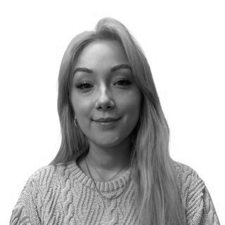 Woman with long blonde hair smiling, wearing a cable-knit sweater.