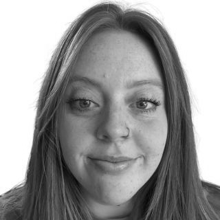 Woman with long hair, smiling, looking at the viewer; nose ring, close-up shot.