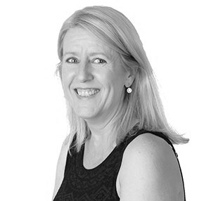 Blonde woman smiling, wearing black top and pearl earring. Studio shot, head and shoulders.