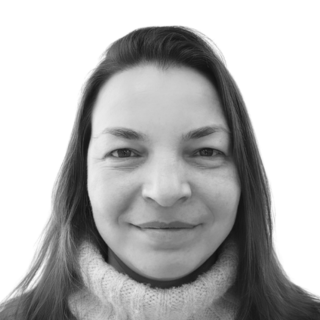 Woman with long hair and a turtleneck smiling at the camera. Black and white photo.