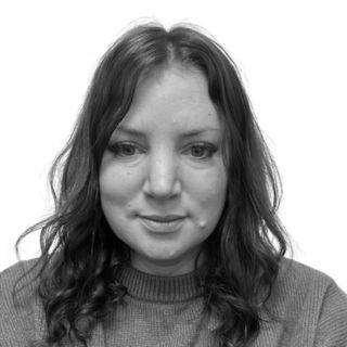 Woman with wavy dark hair, wearing a gray sweater. Black and white photo.