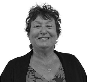 Smiling woman with short, dark hair and a patterned blouse.
