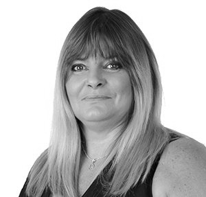 Woman with shoulder-length blonde hair, bangs, and a slight smile, in a black top, against a white background.