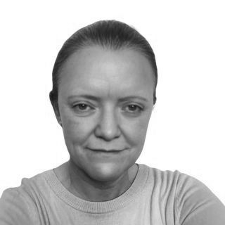 Woman with light skin and a neutral expression, in a gray t-shirt.