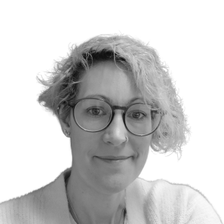 Woman with glasses, light hair, smiling slightly, facing the camera.