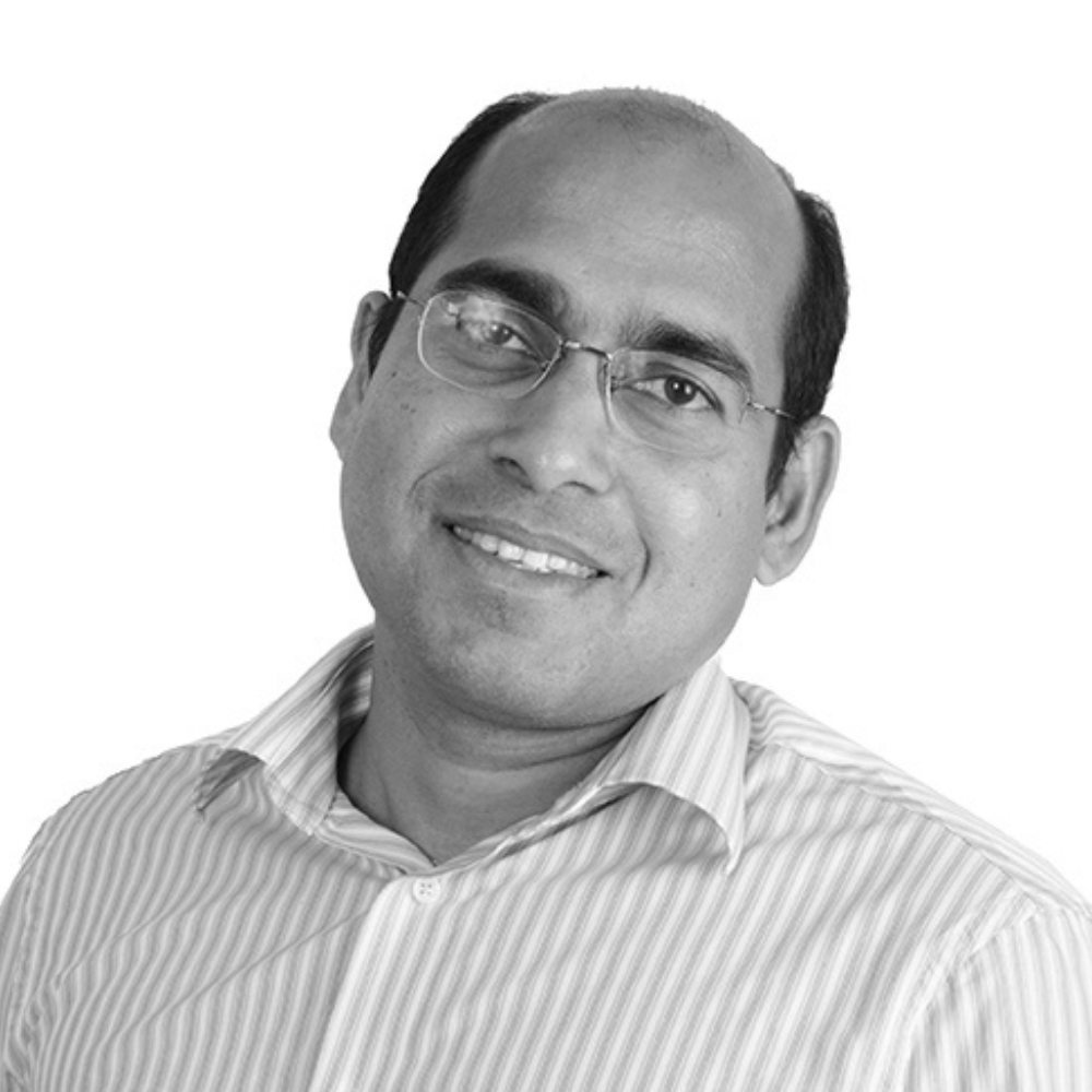 Smiling man with glasses, a bald head, wearing a striped button-down shirt.