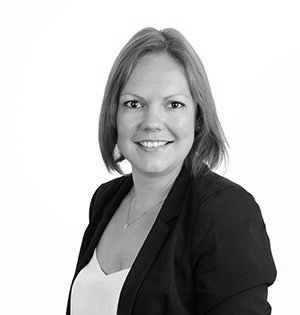 Woman with shoulder-length hair, wearing a dark blazer and white top, smiling at the camera.