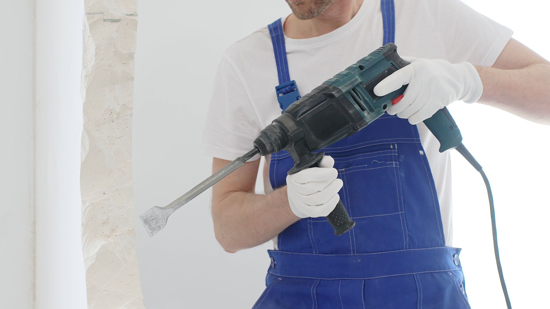 A man is demolishing a wall with a drill.