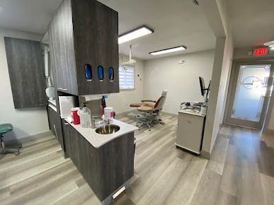 A dental office with a dental chair and a sink.