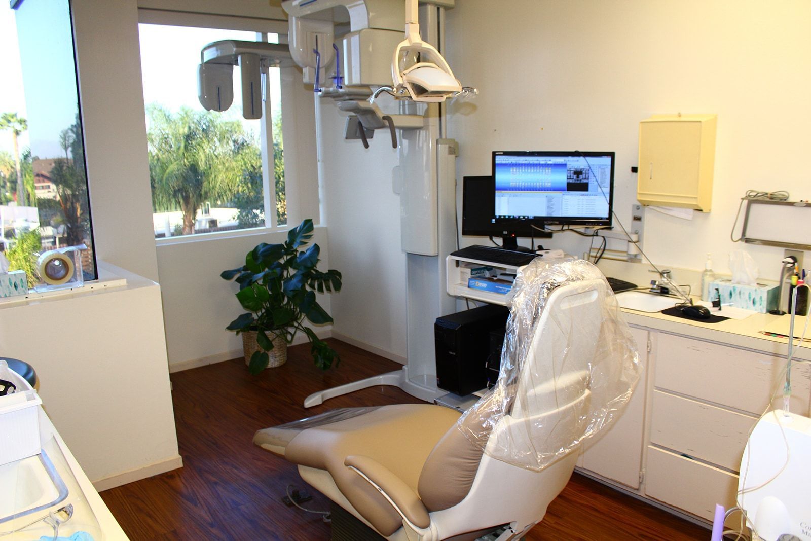 GILROY DENTAL SMILES_Dental examination room with chair, computer, and panoramic X-ray machine.