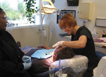 GILROY DENTAL SMILES_Dentist and assistant examining a patient's teeth in a dental office.