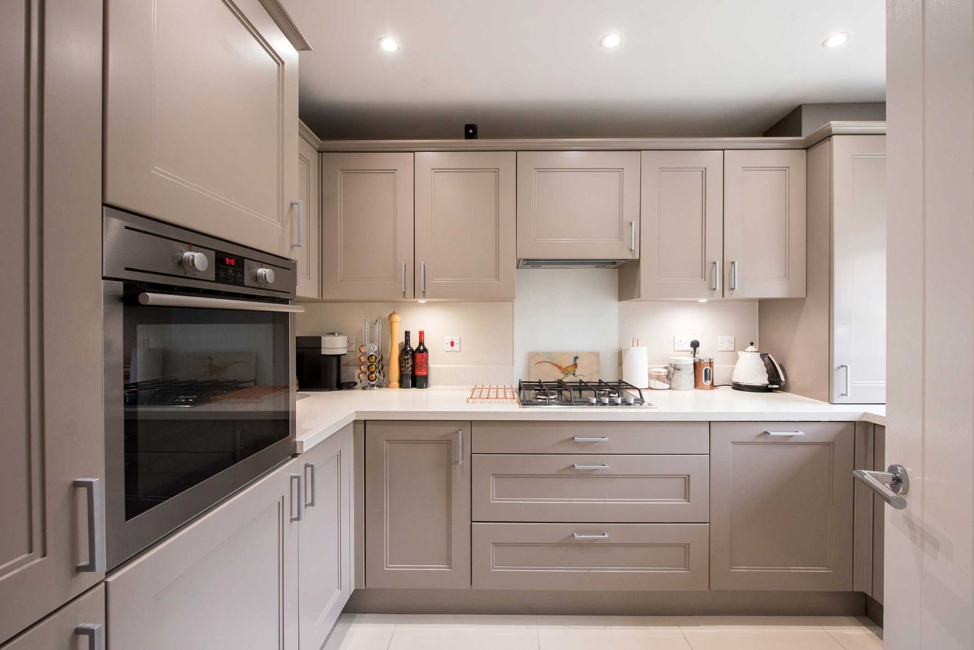 A general interior view of a small truffle-taupe-colored shaker-style fitted kitchen within a home