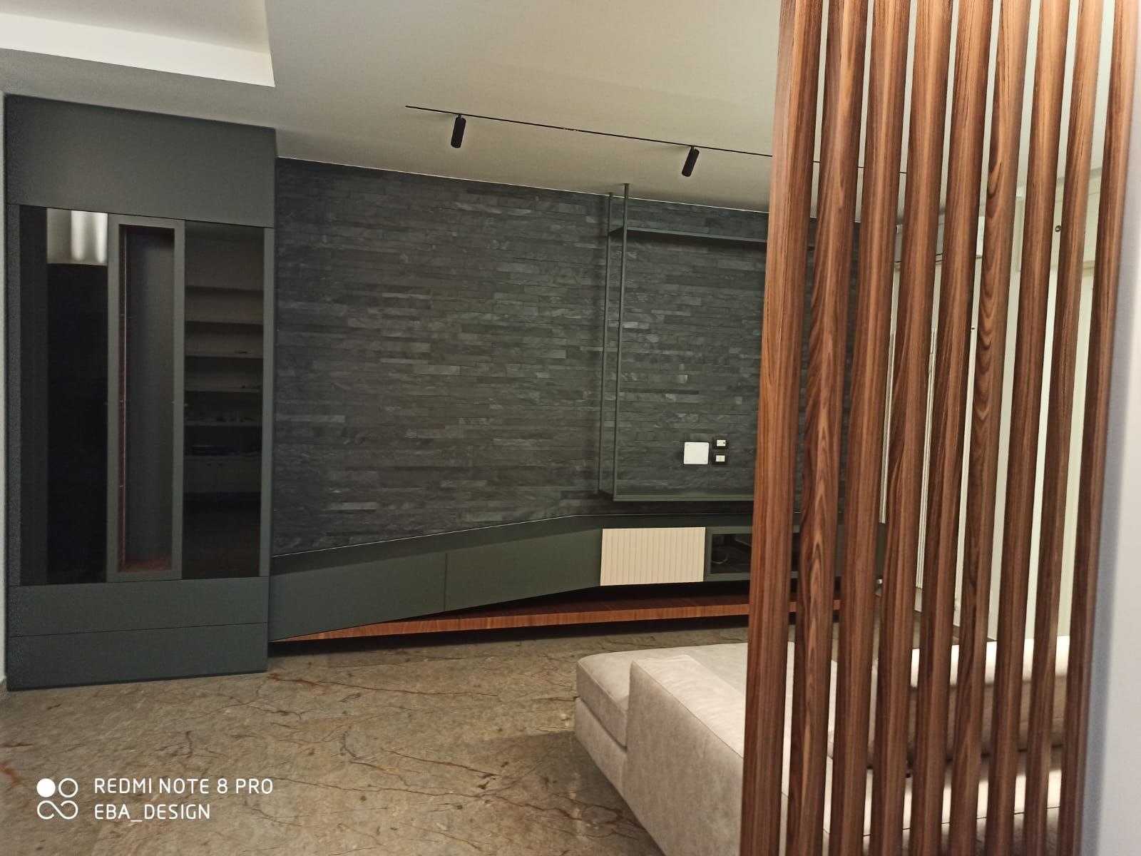 Interno con divisorio in legno a doghe, parete in pietra e mobili moderni.