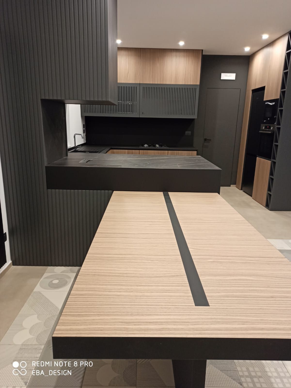 Cucina moderna con mobili in legno e neri. Isola con piano di lavoro in legno e dettagli neri.