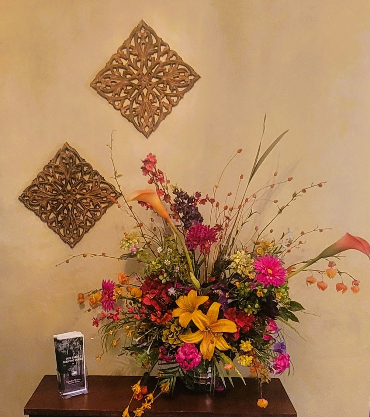 Floral arrangement on a table, with decorative wall squares.