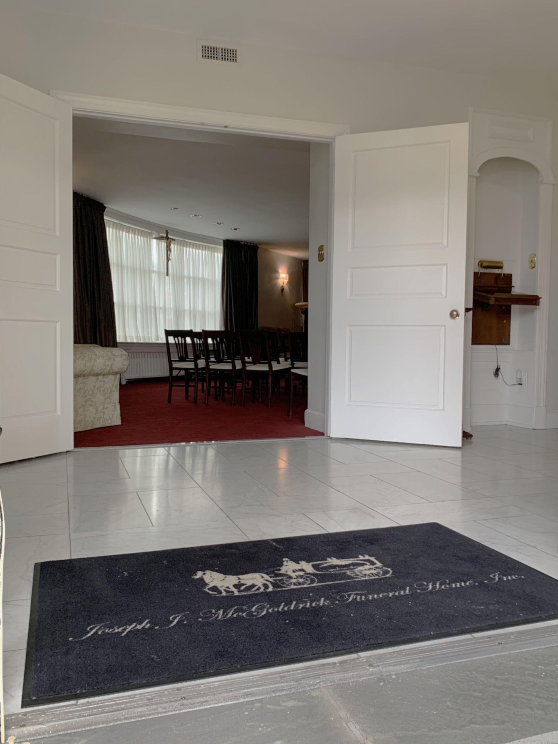 Entrance to Joseph J. Earthman Funeral Home, with open doors, doormat, and red carpet.