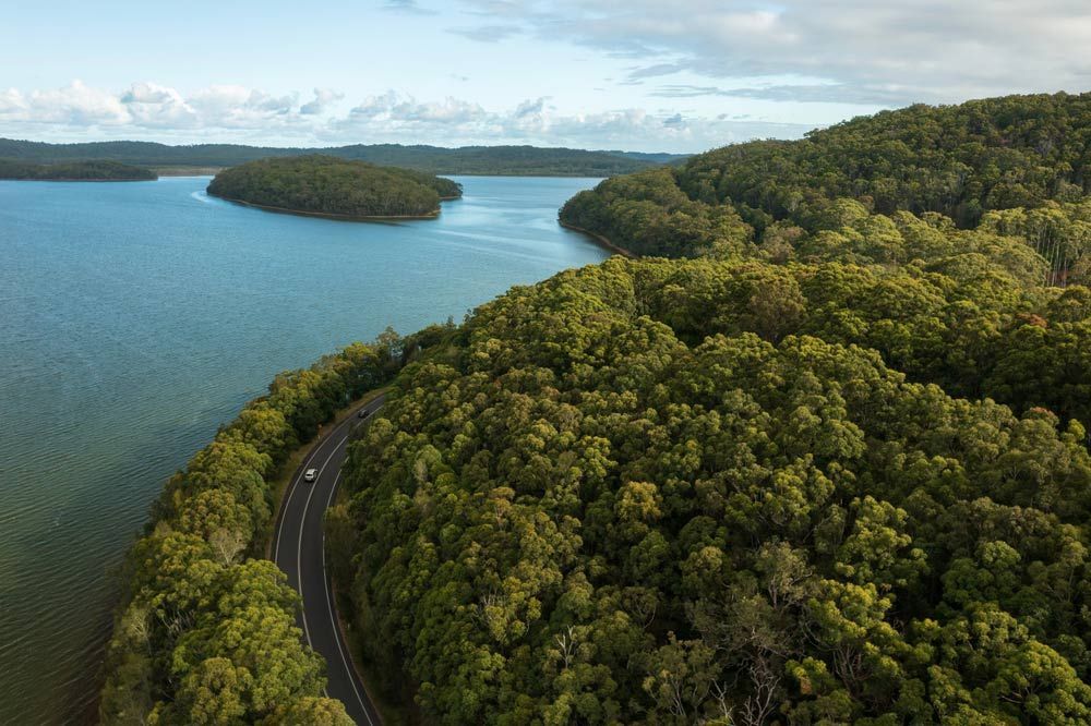 An Aerial View of a Road Going Through a Lake Surrounded by Trees — Great Lakes Mowers & Chainsaws In Smiths Lake, NSW