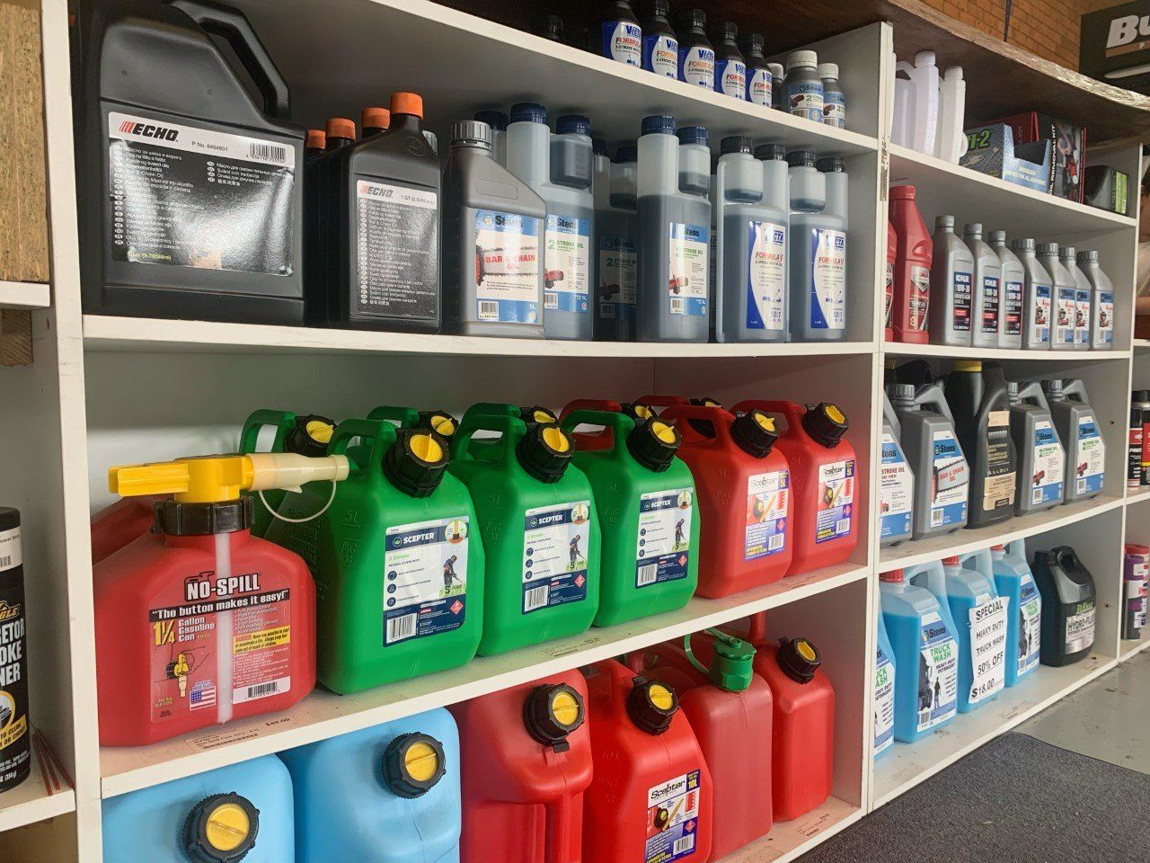 A Shelf Filled With Lots of Different Types of Gas Cans and Bottles — Great Lakes Mowers & Chainsaws In Tuncurry, NSW