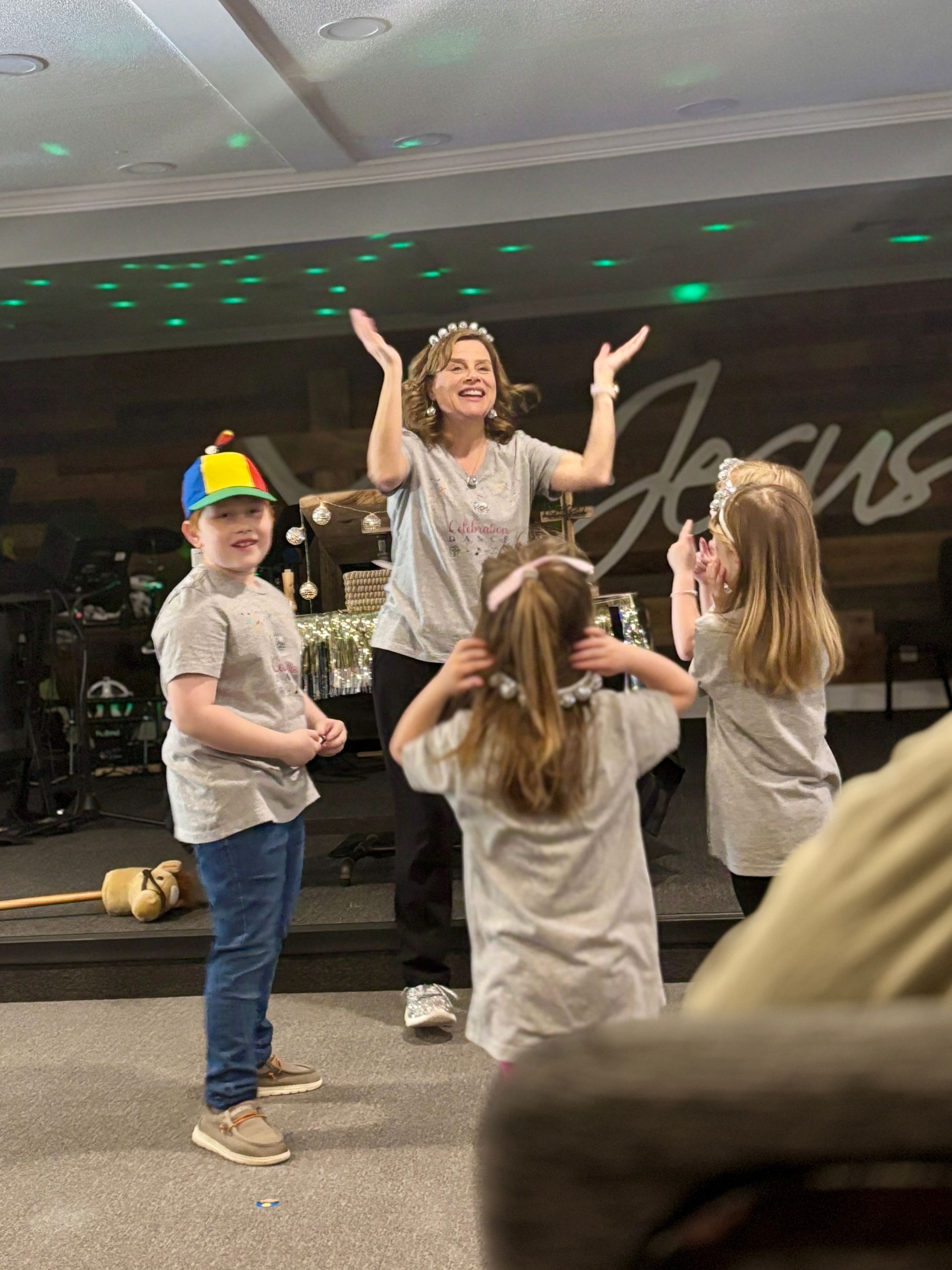 A woman with three children dancing on a stage in front of a 