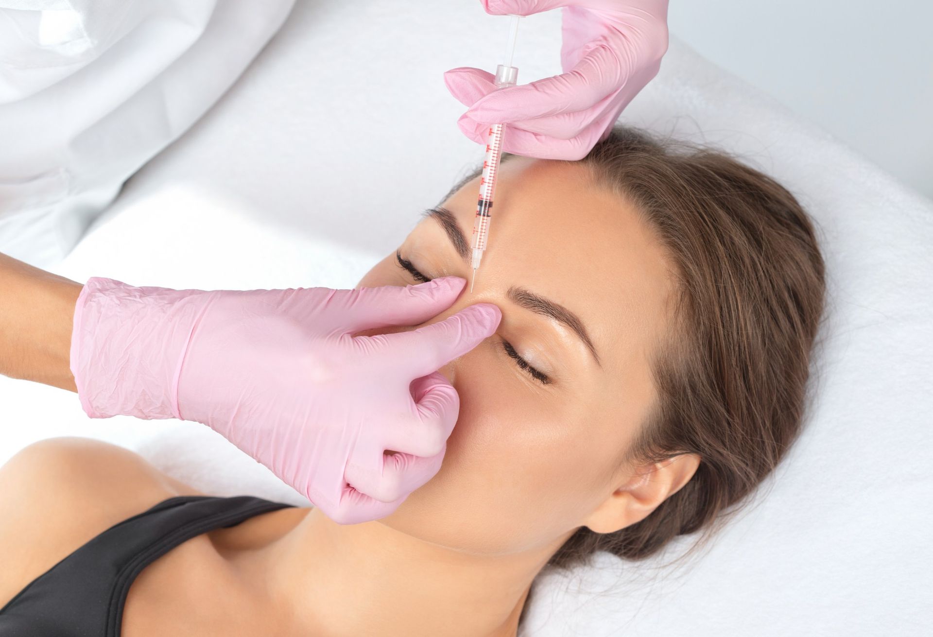 A woman is getting a botox injection in her forehead.