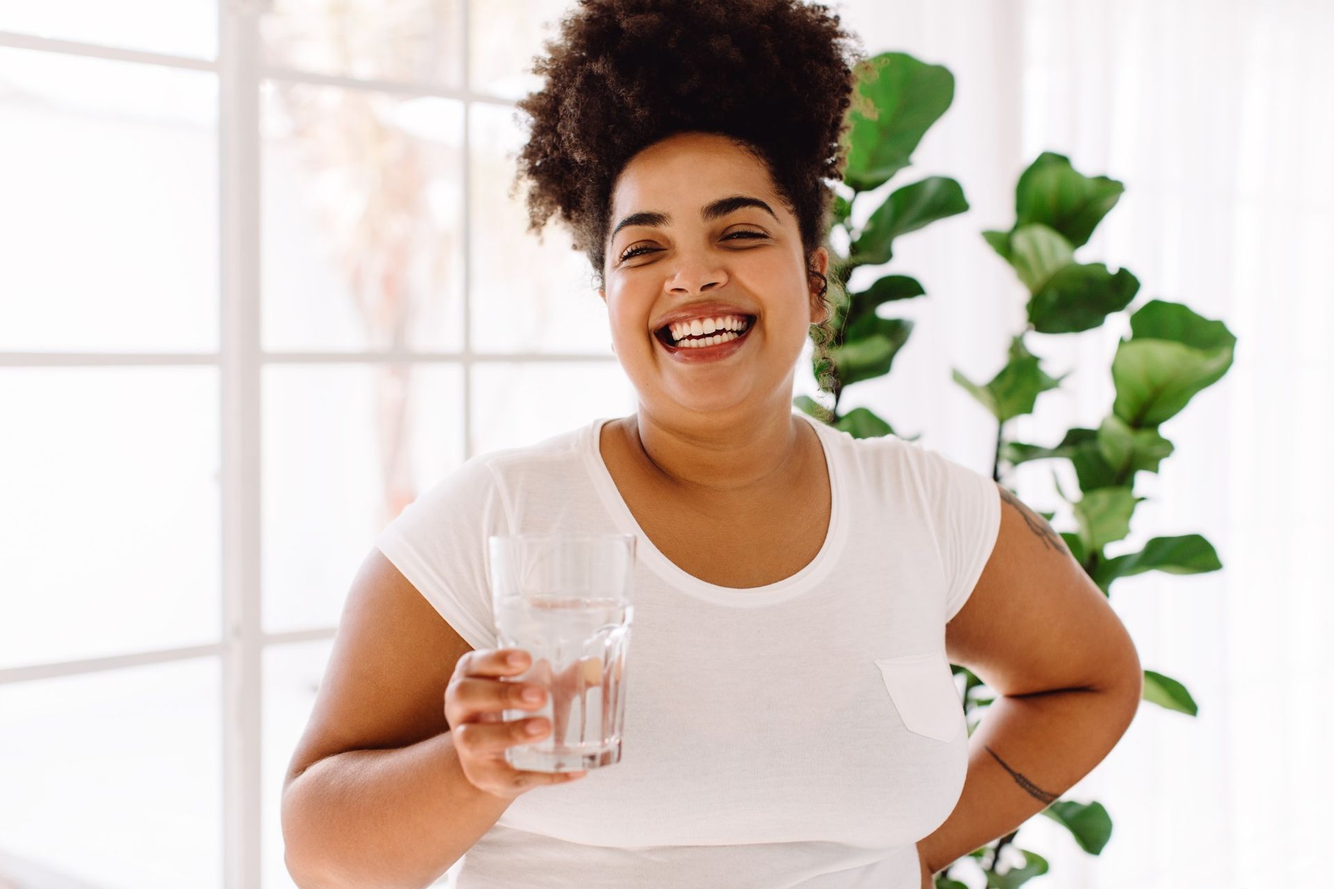 A woman is holding a glass of water and smiling.