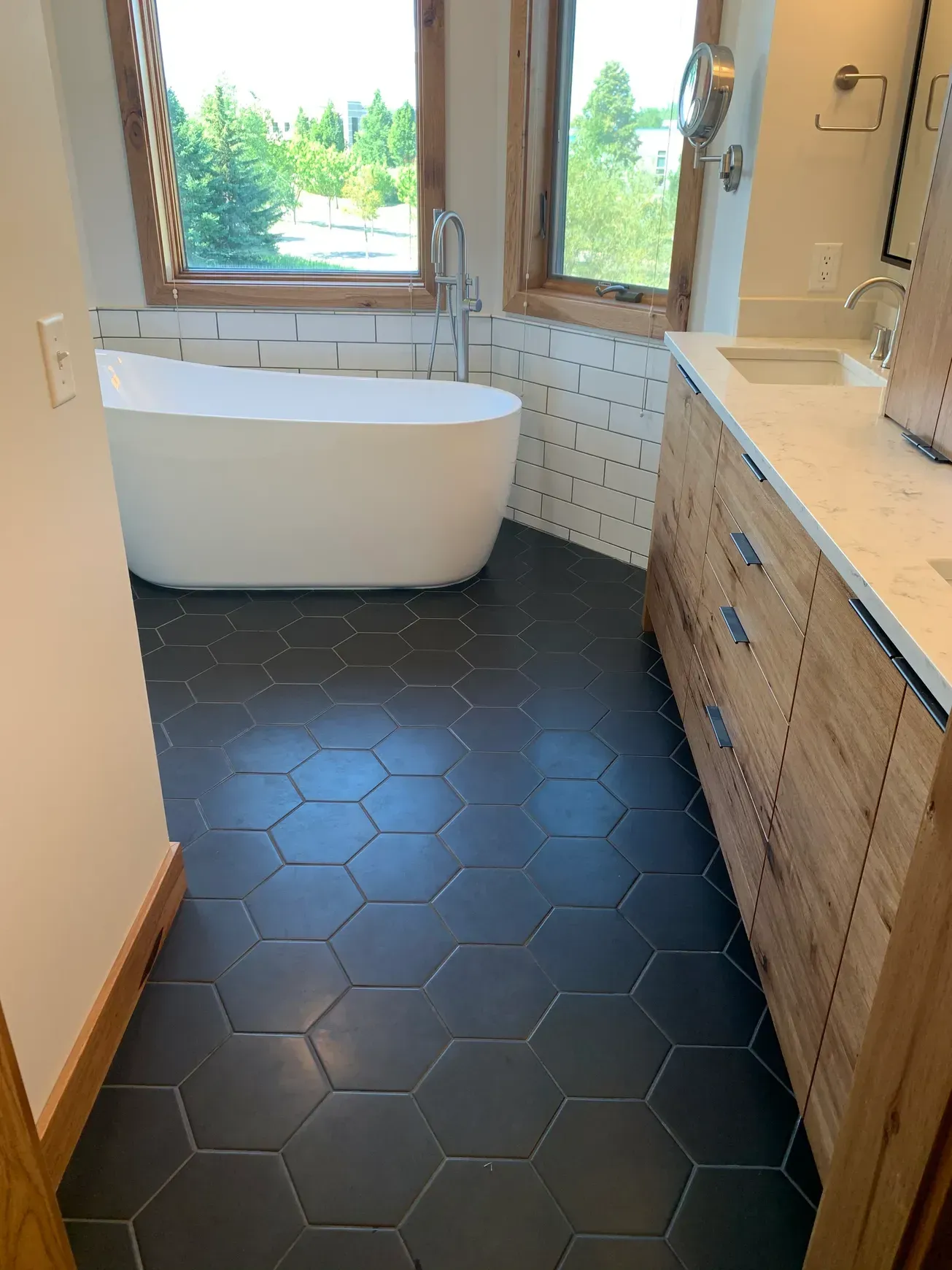 A bathroom with a tub , sink , and window.