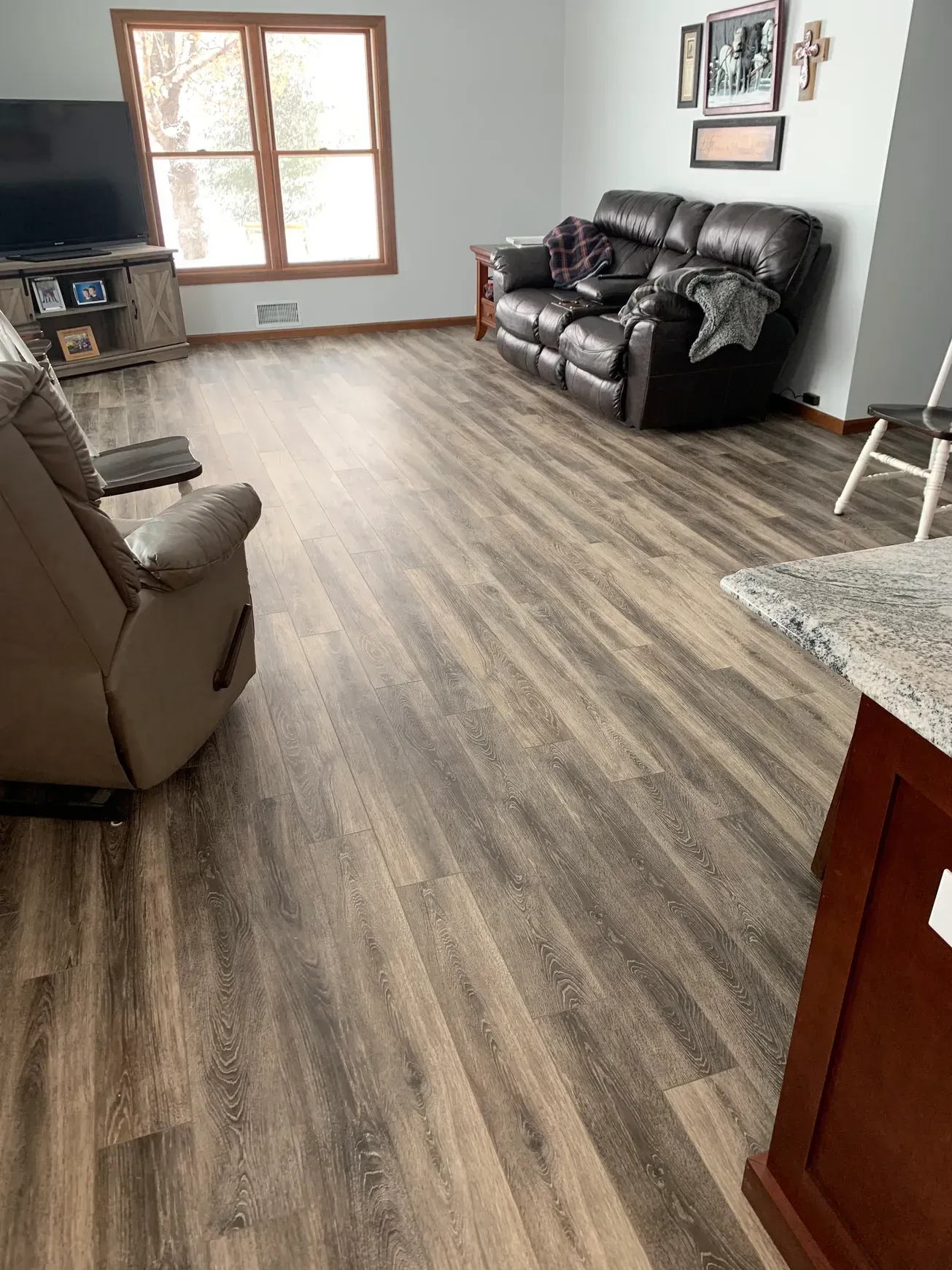 A living room with hardwood floors , a couch , chair and television.