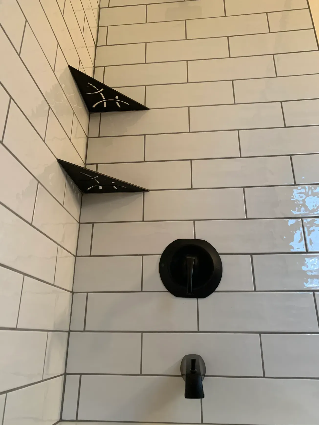 A shower with white tiles and a black faucet