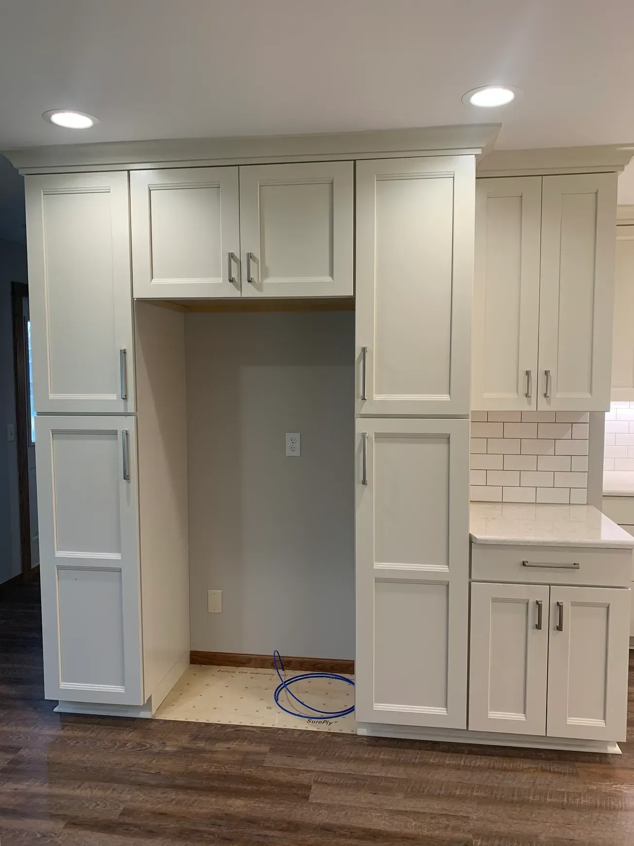 A kitchen with white cabinets and a brick wall