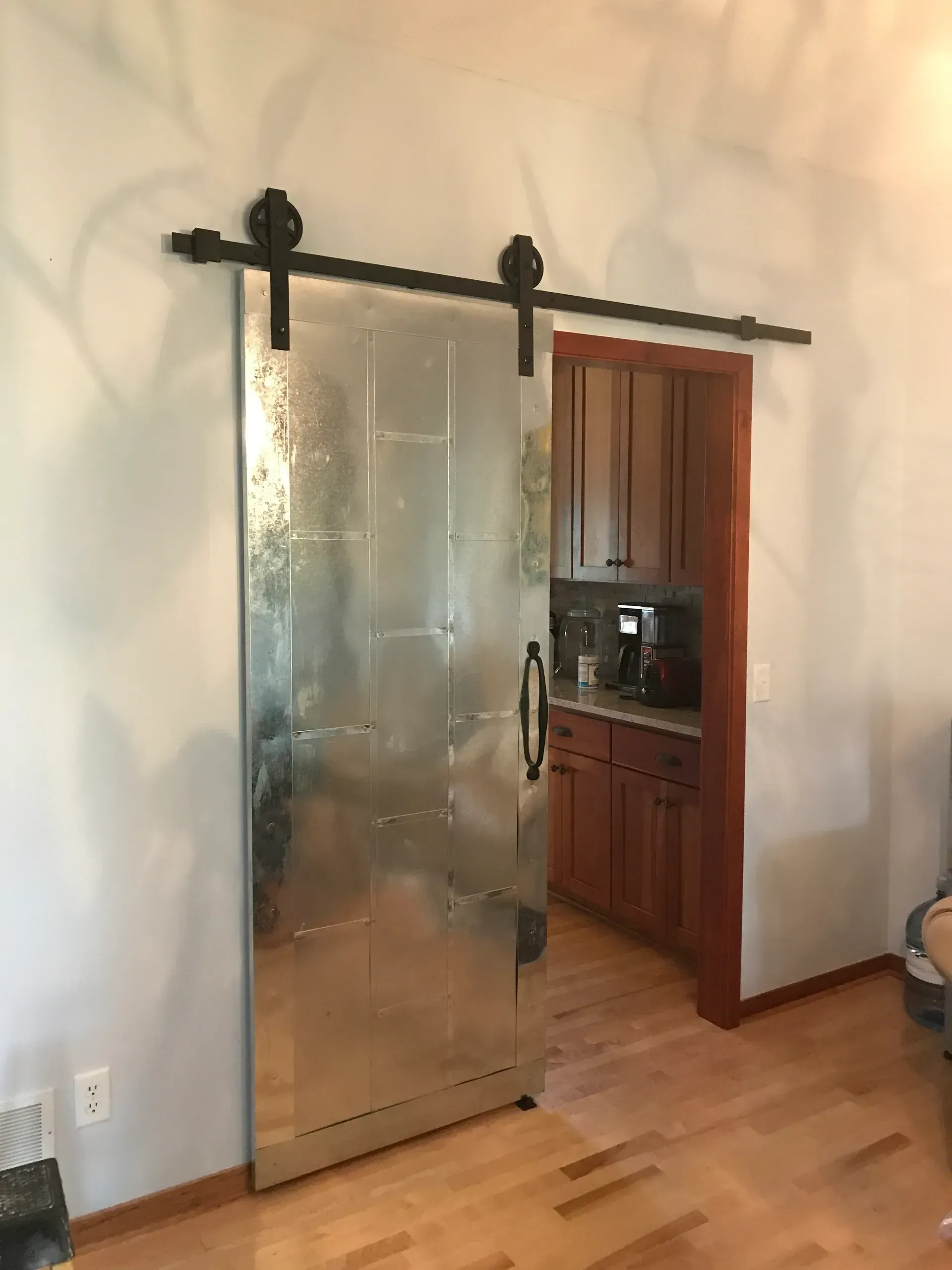 A sliding barn door in a living room leads to a kitchen.