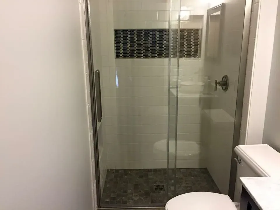 A bathroom with a toilet , sink and walk in shower.