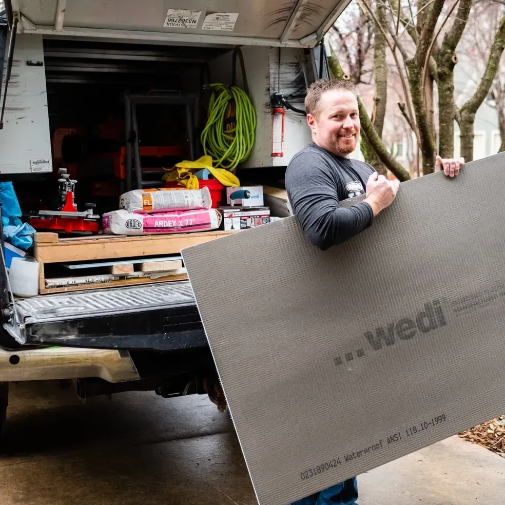 A man is holding a large piece of cardboard that says wedi