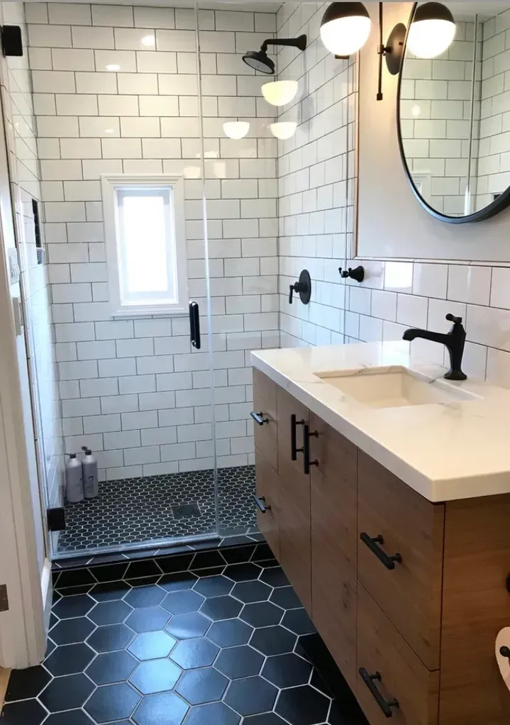 A bathroom with white tiles , a sink , and a walk in shower.