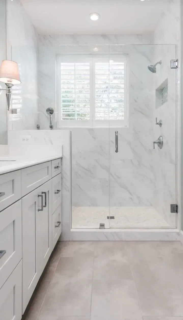 A bathroom with a walk in shower , sink , and window.